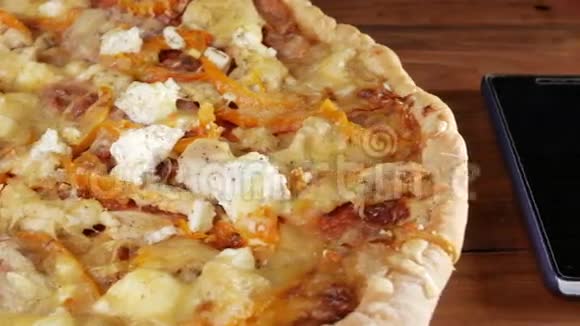 手机放在一张木制桌子上旁边是一个自制的披萨里面有不同的奶酪和西红柿移动摄像机视频的预览图