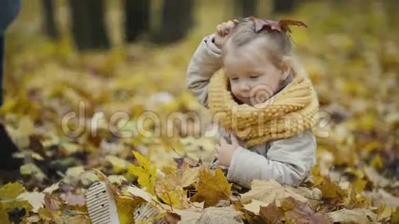 妈妈和女儿在一个秋天的公园里玩扔树叶宝宝的笑声视频的预览图