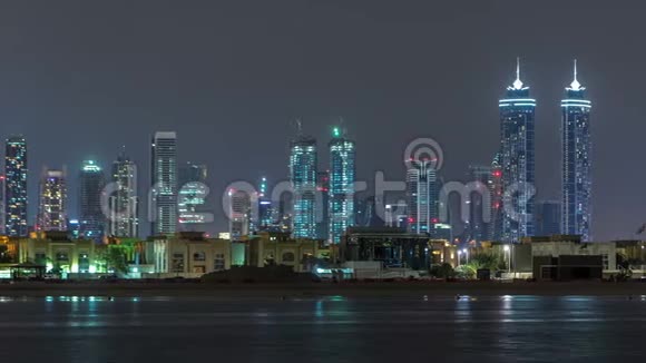 现代迪拜城市的天际线在夜晚随着明亮的摩天大楼在水面上消失视频的预览图