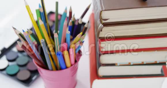彩色铅笔放在笔筒里和一堆书视频的预览图