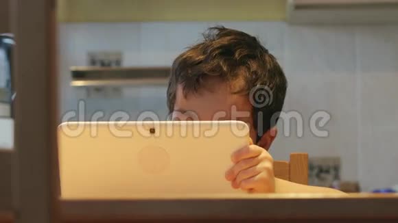 机器人图片一个可爱的小孩手拿一台白色平板电脑在家里的一张桌子上休闲服装视频的预览图