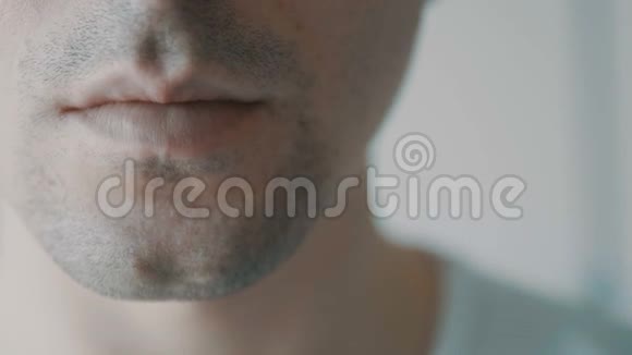 年轻的成年男子特写镜头对着他的嘴说话视频的预览图