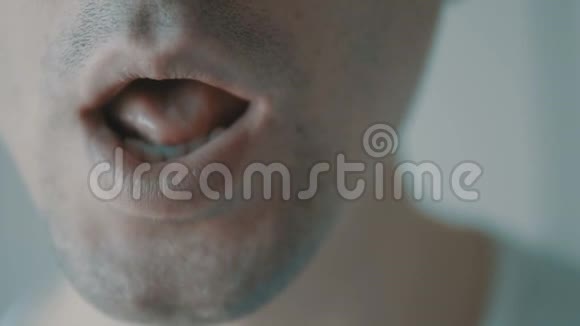 年轻的成年男子特写镜头对着他的嘴说话视频的预览图
