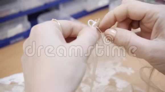 特写珠子和亮片针线刺绣图案缝制优雅婚纱的设备手视频的预览图