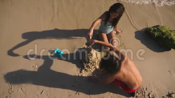 在热带海滩上做沙滩城堡的青少年兄妹视频的预览图