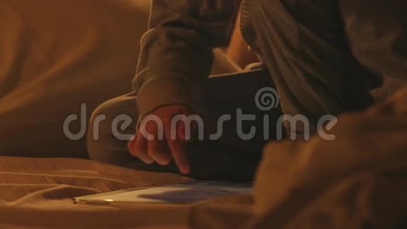 感觉水平一个穿着睡衣的可爱小男孩坐在床上使用平板电脑视频的预览图