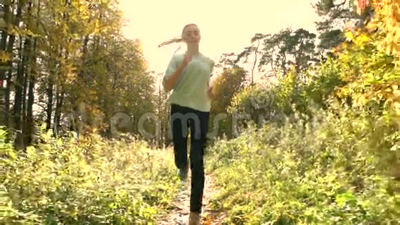 美丽的黑发女孩马尾辫在秋天的森林里奔跑晴天骄阳似火超级慢动作稳定射击视频的预览图