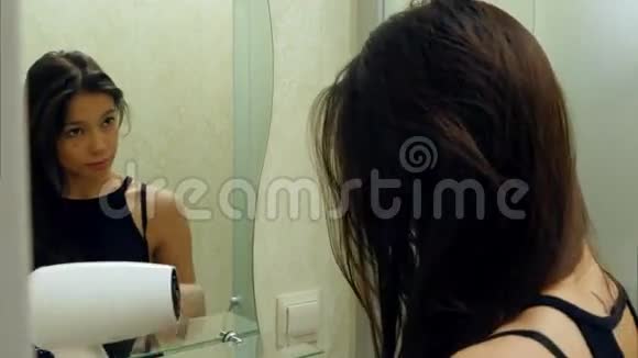 美丽的黑发女孩在浴室里晒头发照镜子视频的预览图
