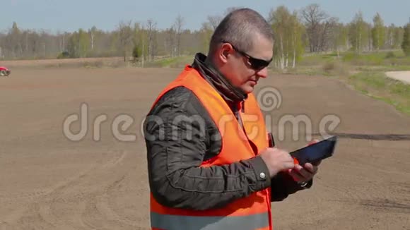 农民使用平板电脑在田间拖拉机耙地视频的预览图