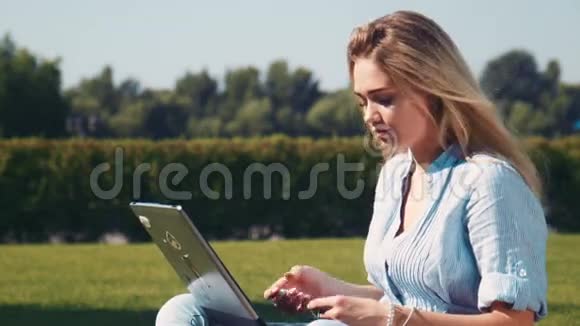 在草地上戴着耳机的微笑女孩视频的预览图