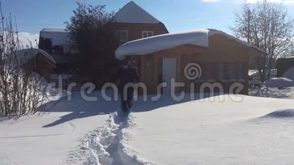 一个人穿过大雪漂流在大自然上在白雪覆盖的房子背景下跳入雪中高清高清视频的预览图