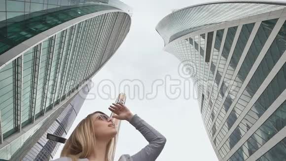 一个金发女孩走着欣赏市中心的摩天大楼和高层建筑慢动作射击视频的预览图