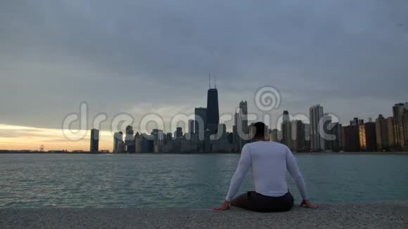 人正坐在河堤上眺望大海和闹市市中心背景是摩天大楼视频的预览图