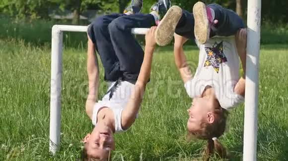 家庭运动小男孩和小女孩在足球场上做运动在单杠上做运动视频的预览图