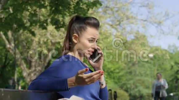 在阳光公园里一幅不开心的心烦意乱的年轻女人在手机上聊天的肖像视频的预览图