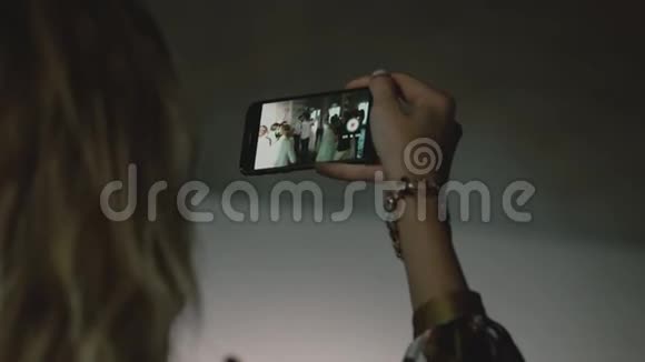女人手拿着手机拍跳舞的人的照片视频的预览图