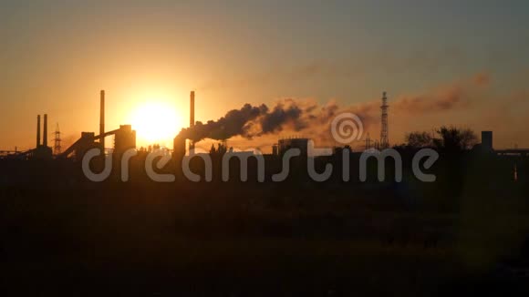 黎明时分太阳背景下工厂管道中的烟视频的预览图