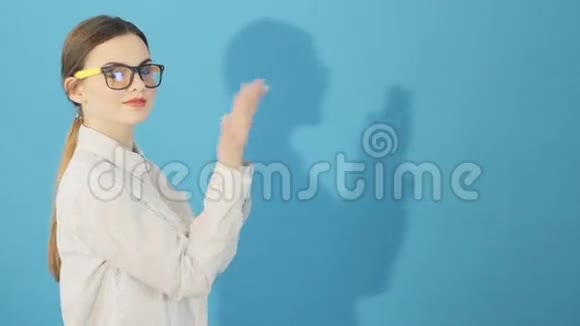 摄影棚里穿衬衫的年轻不安分的女人的肖像带眼镜马尾和长发的布鲁内特侧视图视频的预览图