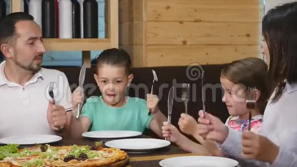 服务员把美味的披萨放在桌子上一个幸福的家庭开始吃近点视频的预览图