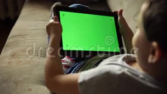 儿童向左和右倾斜一个带有绿色屏幕的平板电脑后视视频的预览图
