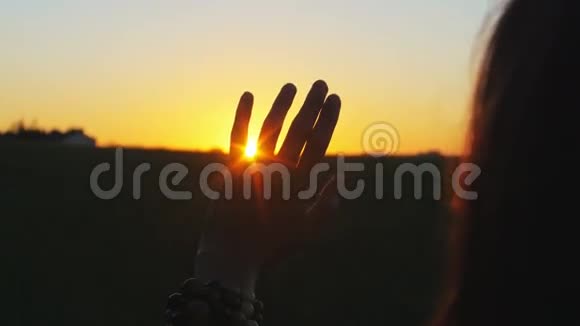 从手中升起女人的手在地平线上美丽的日出上捕捉太阳假期概念4k视频的预览图