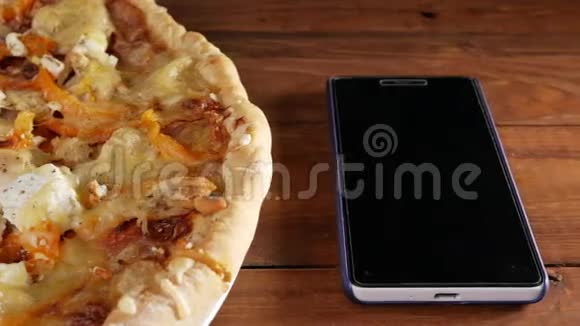 手机放在一张木制桌子上旁边是一个自制的披萨里面有不同的奶酪和西红柿移动摄像机视频的预览图
