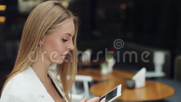 女人在咖啡馆的桌子旁坐着一块平板电脑视频的预览图