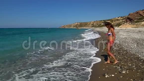 美丽的少女把鹅卵石扔进海里视频的预览图