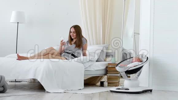在休产假期间在白色卧室里从事网上购物睡在婴儿旁边视频的预览图