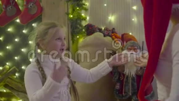 父母和女孩欢呼男孩穿着圣诞老人套装在室内圣诞树附近玩得开心视频的预览图