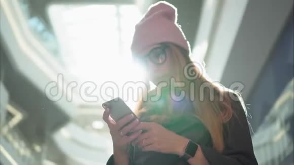 一位年轻的时髦女性在大商场的智能手机上使用应用程序视频的预览图