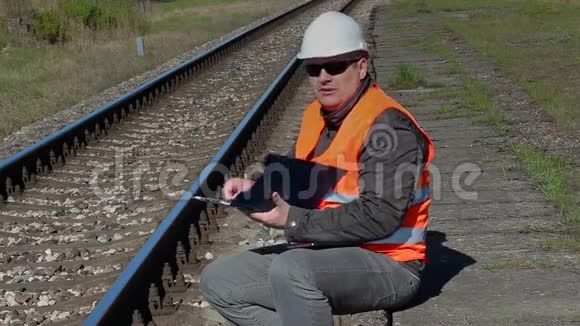 铁路工人坐在铁路附近写作视频的预览图