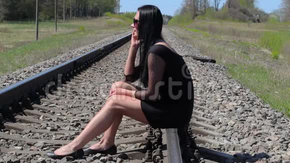 坐在铁路上用智能手机说话的女人视频的预览图