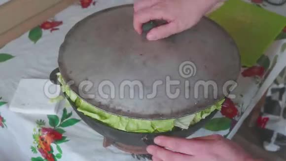 白色男性厨师的手把盖子放在大锅里的蔬菜上然后按下它视频的预览图