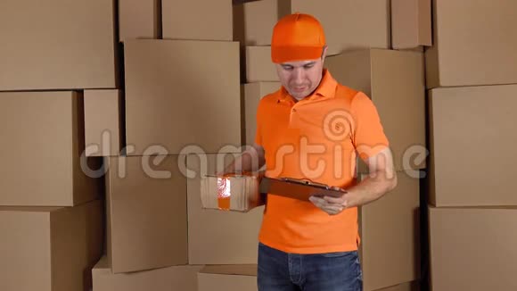 穿橙色制服的人把严重损坏的包裹寄给顾客棕色纸箱背景不专业的工作视频的预览图