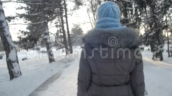 穿着温暖的帽子和围巾在冬季公园散步的年轻漂亮女士视频的预览图