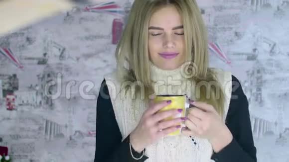 美丽的金发年轻女人在暖和喝咖啡视频的预览图