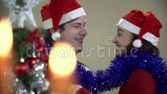 一对夫妇在圣诞节期间用装饰好的树和灯玩乐视频的预览图