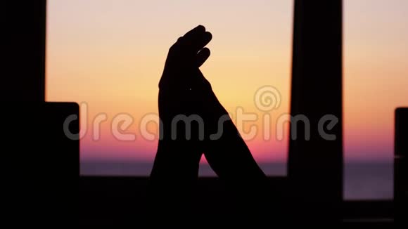 一对夫妇的剪影手相握在窗前的大海和美丽的日落的背景下慢慢慢慢视频的预览图
