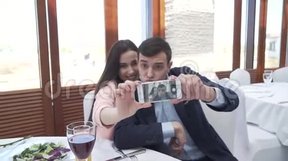 一对情侣在餐厅用智能手机拍自拍股票视频视频的预览图