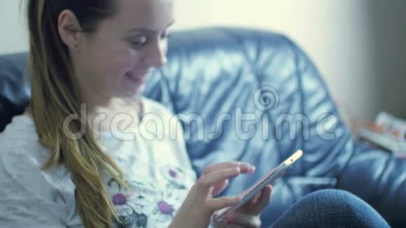 美丽的白种人女人坐在沙发上用手机发短信视频的预览图