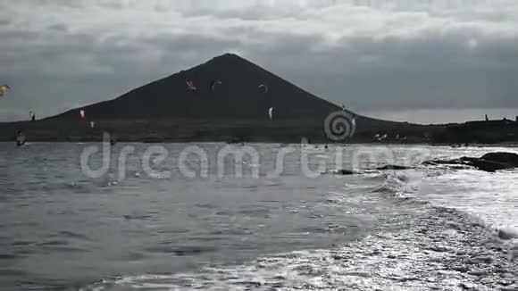 许多五颜六色的风筝在海滩上和风筝冲浪在大风天乘风破浪视频的预览图