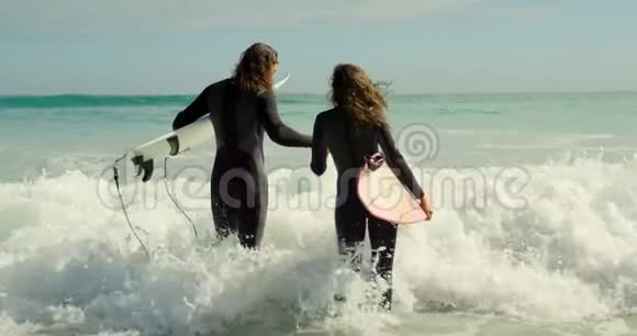 一对拿着冲浪板的情侣双手抱着大海视频的预览图