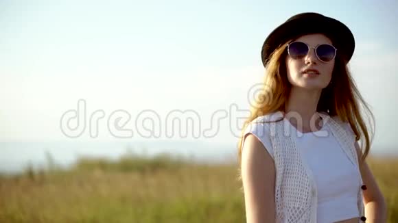 年轻漂亮的女模特戴着帽子戴着太阳镜摆出户外慢动作视频的预览图