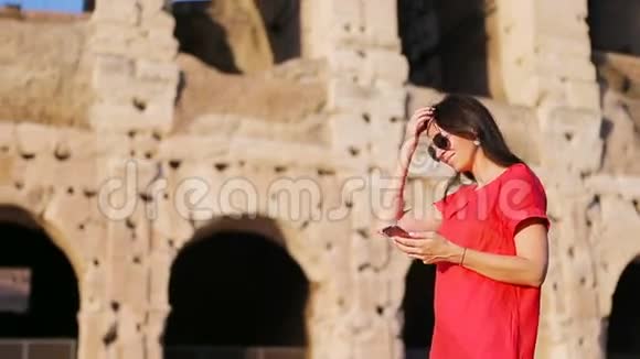 意大利罗马竞技场前的年轻女子手里拿着智能手机欧洲度假女孩视频的预览图