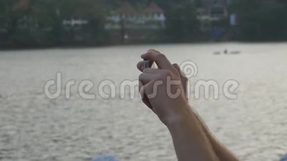 男性手握智能手机拍摄城市景点与河流背景打电话拍照的男人视频的预览图