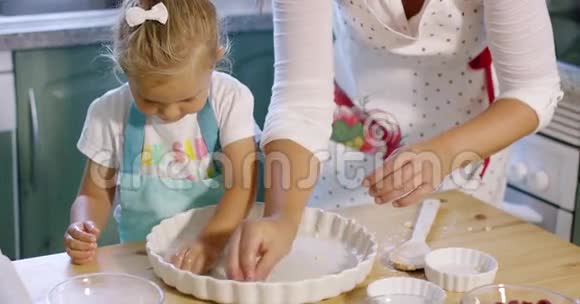 可爱的小女孩在烤盘上涂油视频的预览图
