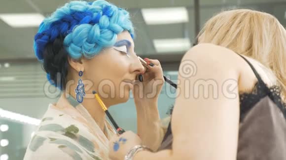一位专业的化妆师在模特的眼皮上作画准备艺术摄影视频的预览图