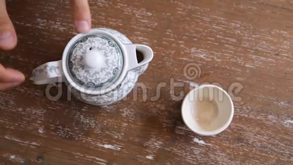 在木桌上用杯中的陈年茶点缓慢地饮用健康绿茶传统仪式视频的预览图
