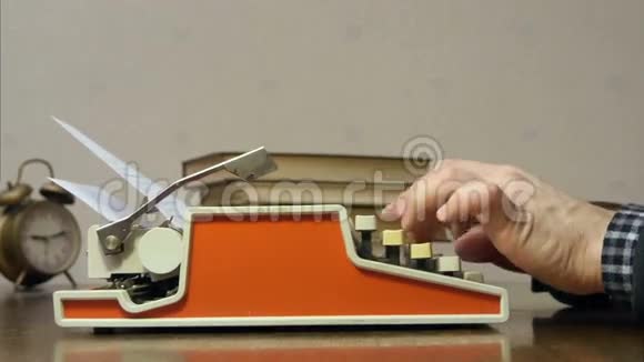 男性用手在书桌前用旧的红色打字机打字视频的预览图